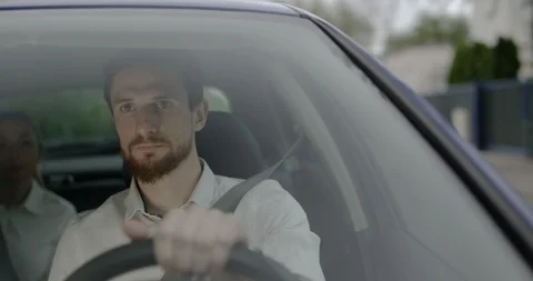Young taxi driver with a beard is checking time while waiting on a red light. Stock Footage 128439713