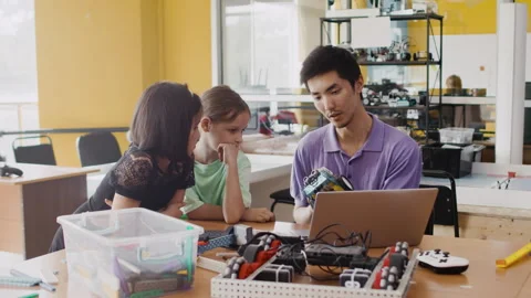 Young teacher explain to the children how to assemble a moving robot in a class Stock Footage 242933888