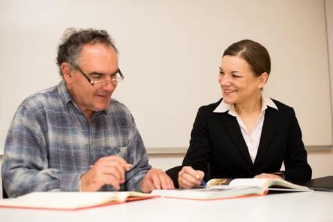 Young teacher explaining somethng to eldery man. Intergenerational transfer o Stock Photos