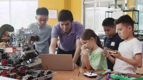 Young teacher explains to children in a class at a robotics lesson how to Stock Footage 242169731