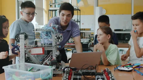 Young teacher explains to the children how to program a moving robot using a Stock Footage 243519048