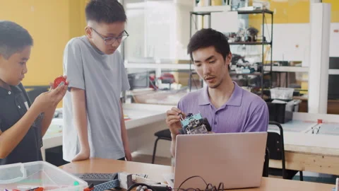 Young teacher explains to the children the structure of a moving robot and Stock Footage 243831522