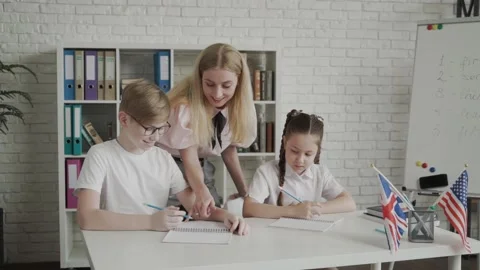 Young teacher helping pupil learning and explaining mistakes. Teacher between Stock Footage 134899767