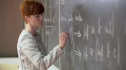 Young teacher lectures at the School of Mathematics, writes chalk on a Stock Footage 118994503