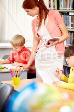 A young teacher looking after her working student Stock Photos