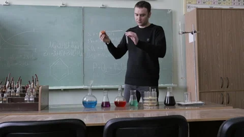 Young Teacher Or Student Conducts Laboratory Chemical Experiments In Test Tubes Vidéo 328609916