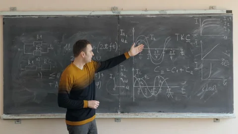 Young teacher or student explaining schemes and graphics near the blackboard Stock Footage 91901406
