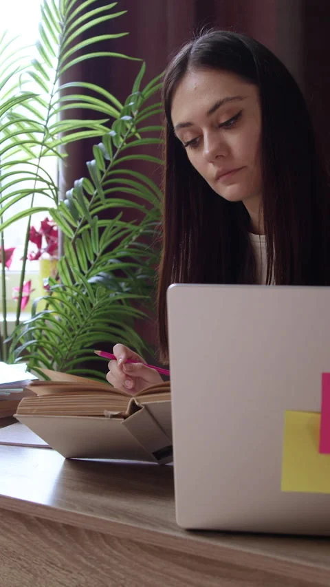 Young teacher prepares material for lessons with students at home in an oasis of Stock Footage 305408265