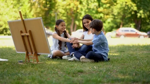 Young teacher unites student while they sitting on grass in outdoor lesson Stock Footage 126293300