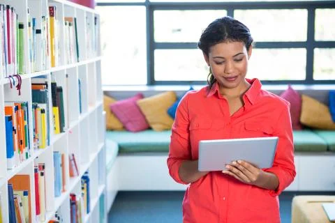 Young teacher using digital tablet at library in school 스톡 사진