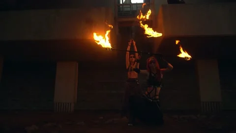 Young team with burning staff doing fire show on concrete background under road 库存影片 194375971