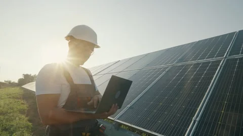 A young technician analyzes the operation of a solar power plant with a laptop Stock Footage 264359435