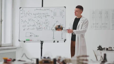 Young technician engineer holding in hand new invention and showing formulas Stock Footage 83749285