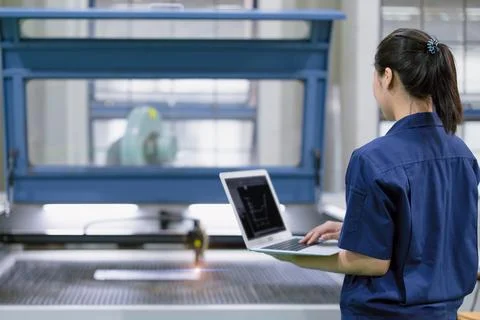 Young technician engineer worker with Metal Laser cutting machine in modern.. Stock Photos