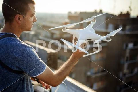 Young technician flying UAV drone with remote control on rooftop Stock Photos