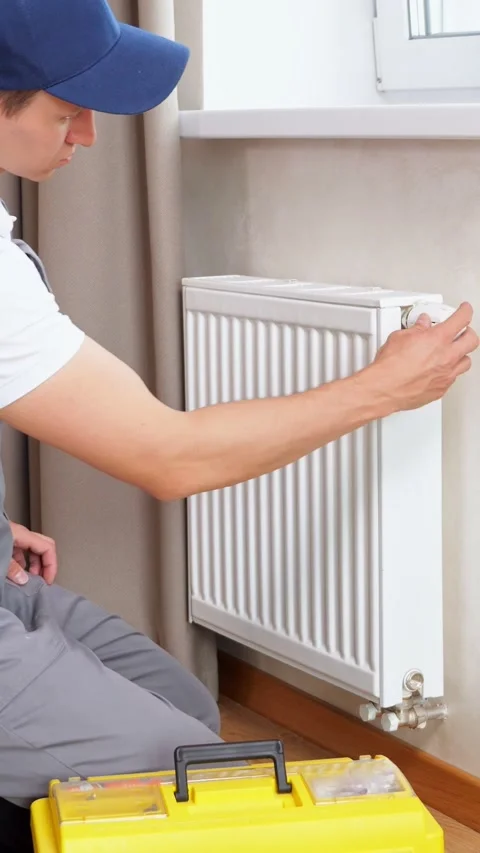 Young Technician Inspects Home Radiator While Diagnosing Heating System Leak Stock Footage 346989366