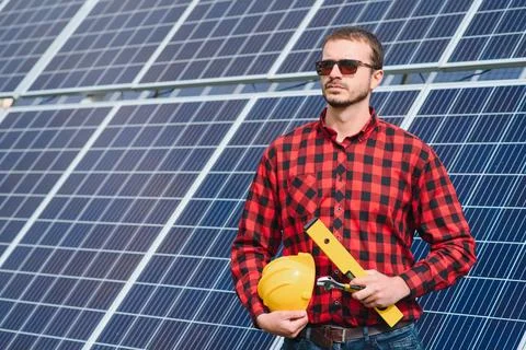 Young technician installing solar panels on factory roof Stock Photos