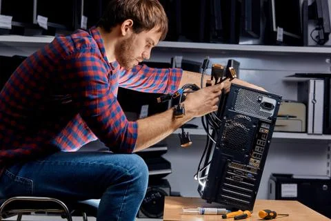 Young technician replacing the wires of the system unit Foto stock