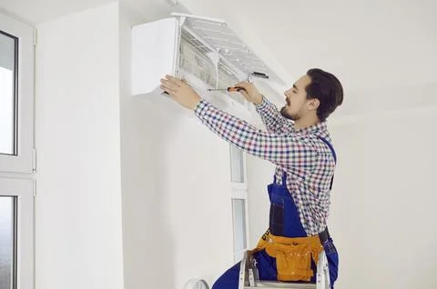 Young technician using a screwdriver while repairing an air conditioner on the Foto stock
