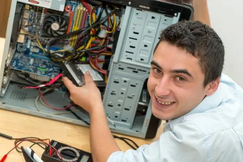 Young technician working on broken computer in his office Stock Photos