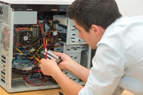 Young technician working on broken computer in his office Stock Photos