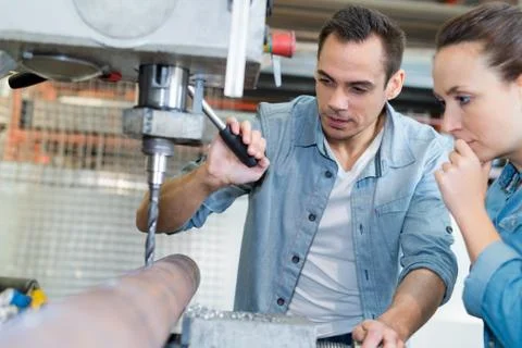 Young technicians working on pillar drilling machine in workshop Stock Photos
