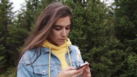 Young teen coed using touch screen smartphone while in nature. Hipster using Stock Footage 95832363