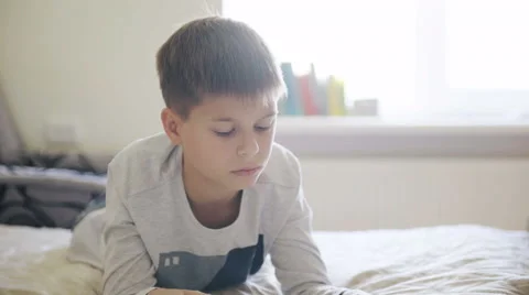 Young teenage boy looking at digital tablet in bed Stock Footage