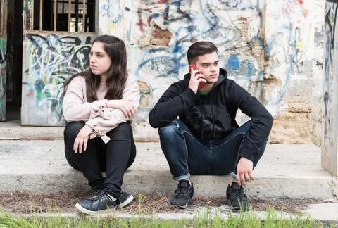 Young teenage boy talking on the mobile phone and ignoring the girl. Conce... Stock Photos