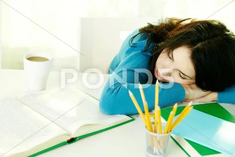 Young teenage girl falling asleep while doing homework Stock Photos