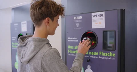 A young teenager hands plastic empty bottles into a machine in exchange for Stock Footage 250246236