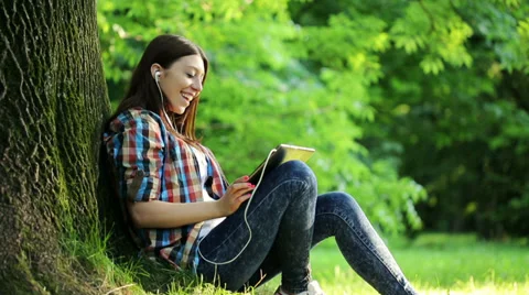 Young teenager watching movie on tablet computer in the park HD Stock Footage