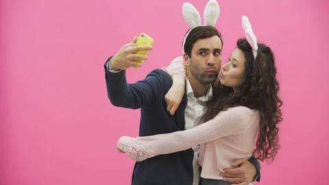 Young tender pair standing on a pink background. Looking at the phone while Stock Footage 104808480