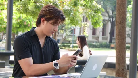 Young Thai Male Student Using Smartphone at Outdoor University Campus Table Stock Footage 329010833