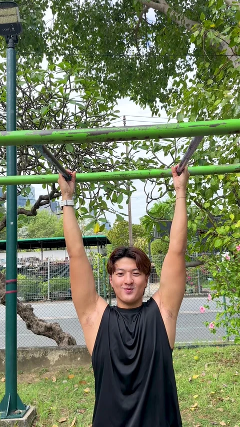 Young Thai Man Performing Pull Ups at Benjakitti Park in Bangkok Stock Footage 332393237