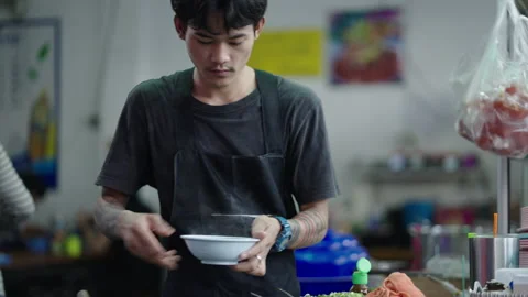 Young Thai man serving noodle soup and smiling to the camera before serving it Vídeo Stock 232327433