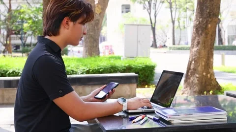 Young Thai Student Using Laptop and Smartphone on University Campus Stock Footage 327885620
