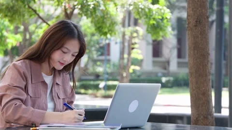 Young Thai University Student Studying with Laptop and Textbook Outdoors Stock Footage 332387844