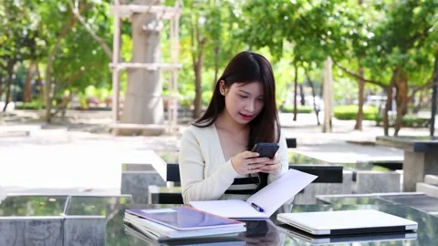 Young Thai University Student Texting on Smartphone While Studying Outdoors Stock Footage 328213258