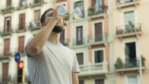 Young Thisty Man Opens Drinks and Enjoys a Bottle of Cold Water Stock Footage 129408315