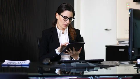 Young thoughtful secretary using a digital tablet at her desk, smiling in the en Stock Footage 126594544