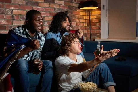 Young Three Men Sitting On Sofa Watching Sport Championship Together Emotionally Stock Photos