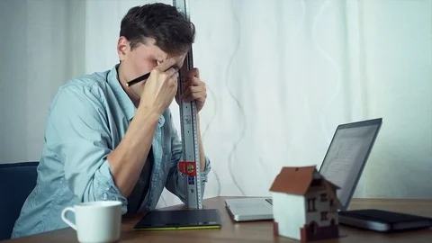 Young tired designer sitting in front of computer with a metal ruler. Stock Footage 79902842