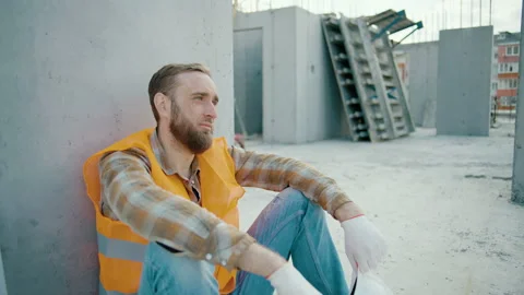 Young tired man worker sitting and takes off white hardhat Stock Footage 241170994