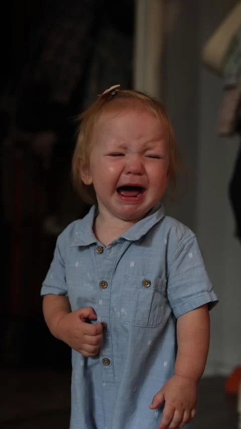 A young toddler crying while wearing a light blue button down shirt in a home Stock Footage 345610974