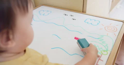 Young toddler develops fine motor skills while drawing on a whiteboard Stock Footage 337956580