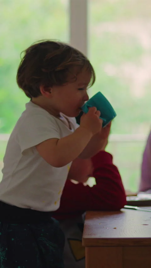 Young toddler drinking from cup at breakfast table, family togetherness, mo.. Stock Footage 336545446