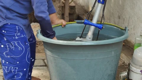 A young toddler is happily learning to walk and is playing in a water bucket. Stockbeeldmateriaal 294197250