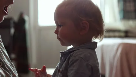 A young toddler interacts with a parent in a sunlit room during a quiet moment Stock Footage 345610323