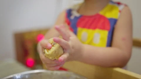 Young toddler learns to bake by rolling cookie dough into a ball in a home Stock Footage 344577526